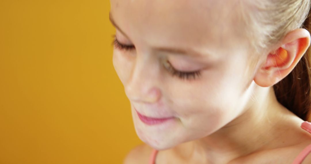 Happy Blonde Girl Smiling with Eyes Closed on Yellow Backdrop