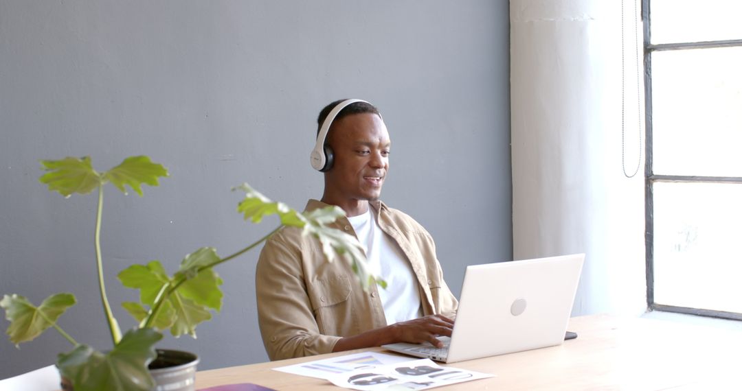 Smiling Professional Wearing Headphones Using Laptop for Video Conference