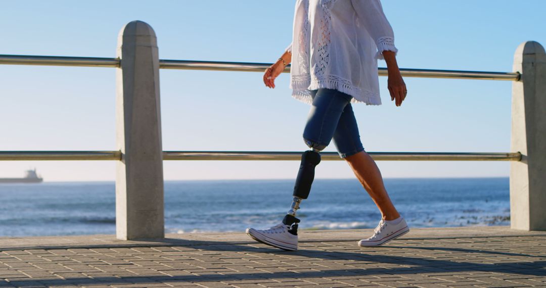 Woman with Prosthetic Leg Walking by the Ocean during Sunny Day - Free Images, Stock Photos and Pictures on Pikwizard.com