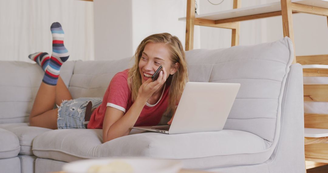 Smiling Woman Relaxing on Sofa with Laptop and Phone on Weekend