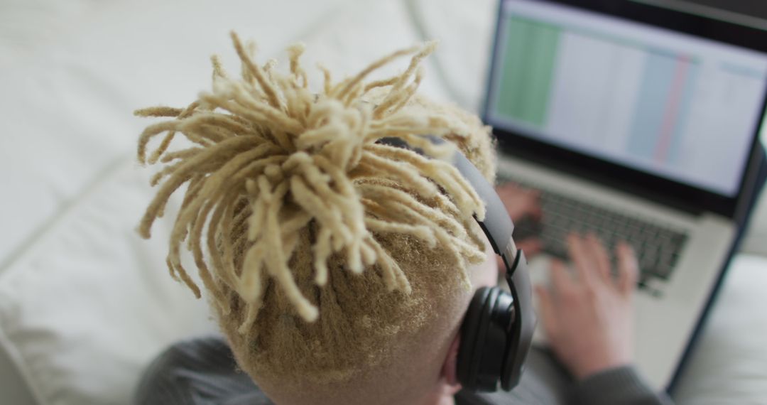 Young Person with Dreadlocks Working on Laptop Wearing Headphones - Free Images, Stock Photos and Pictures on Pikwizard.com