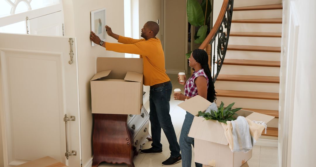 Couple Hanging Picture in New Home Hallway During Move-In