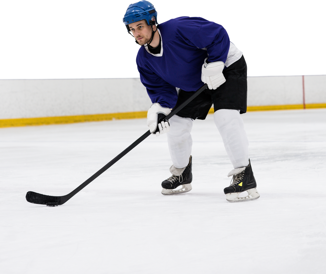 Male ice hockey player navigating puck on snow-neutral packed playing field near arena wall - Download Free Stock Images Pikwizard.com