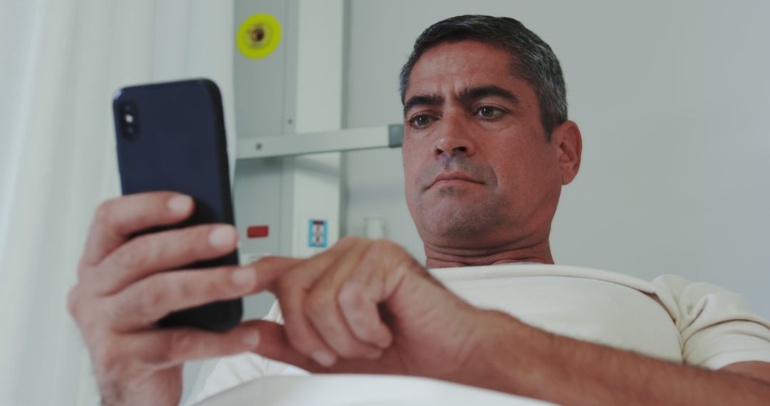 Serious Man in Hospital Using Smartphone for Communication - Free Images, Stock Photos and Pictures on Pikwizard.com