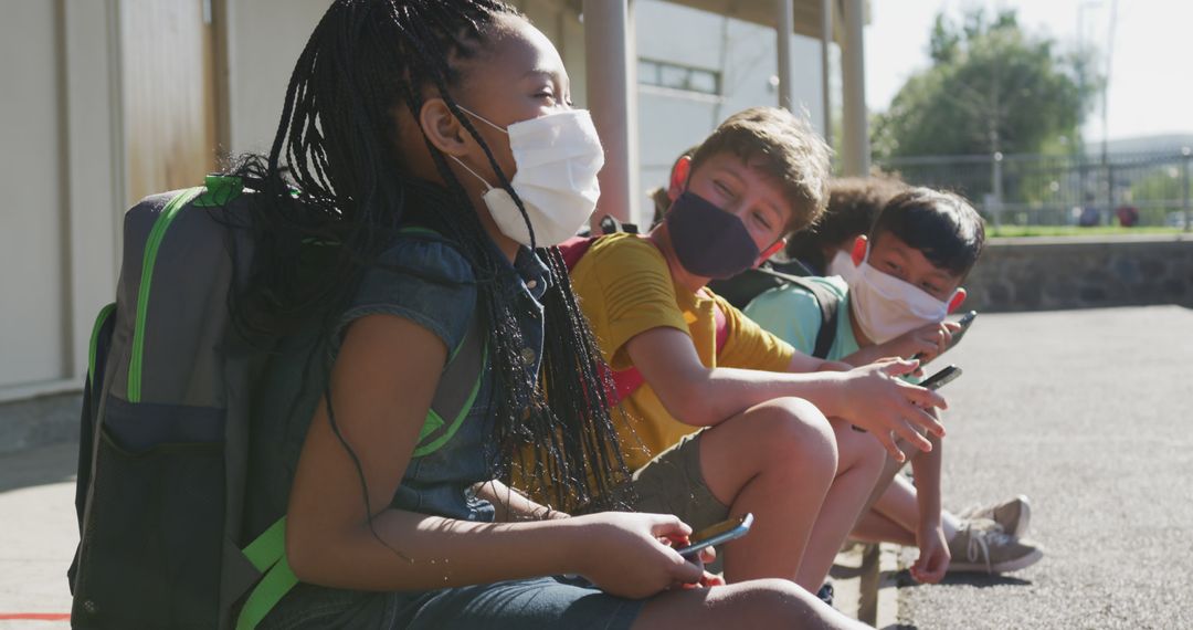 Diverse Students Using Smartphones with Facemasks Outdoors
