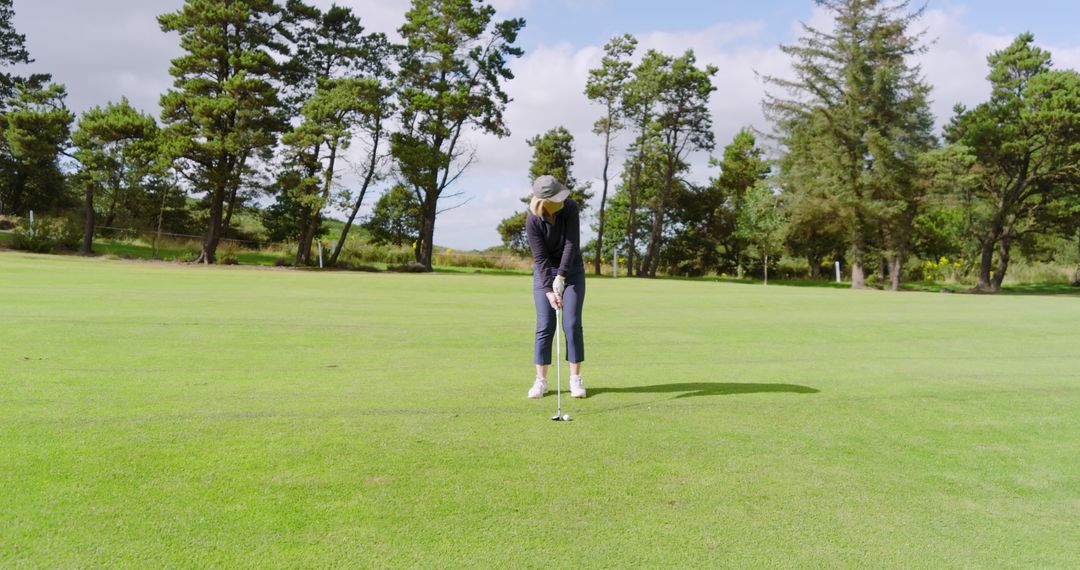 Female Golfer Preparing to Putt on Sunny Green Course