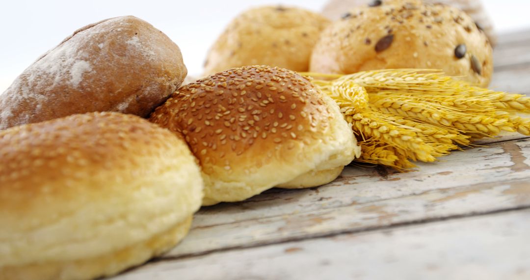 Assorted Fresh Bread Rolls with Wheat Stalks on Rustic Wooden Surface - Free Images, Stock Photos and Pictures on Pikwizard.com