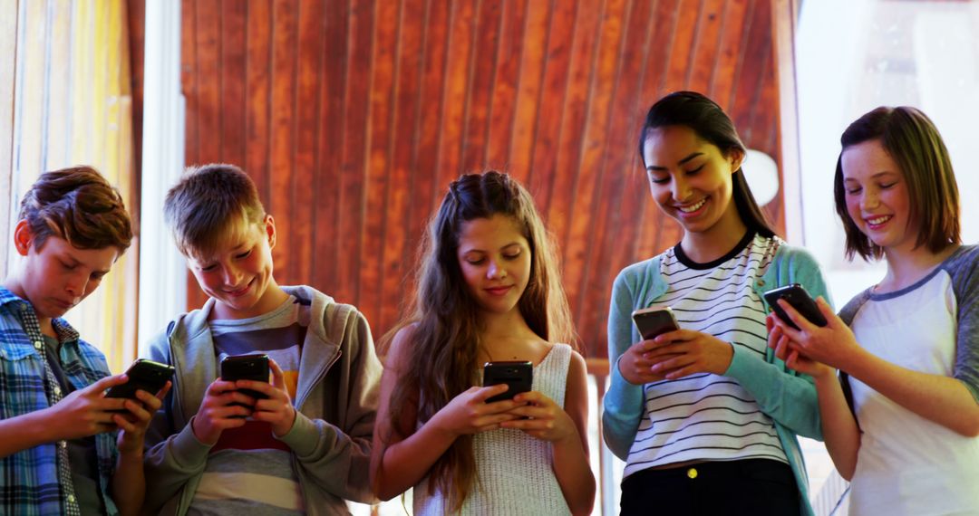 Group of Teenagers Smiling and Using Smartphones Indoors - Free Images, Stock Photos and Pictures on Pikwizard.com