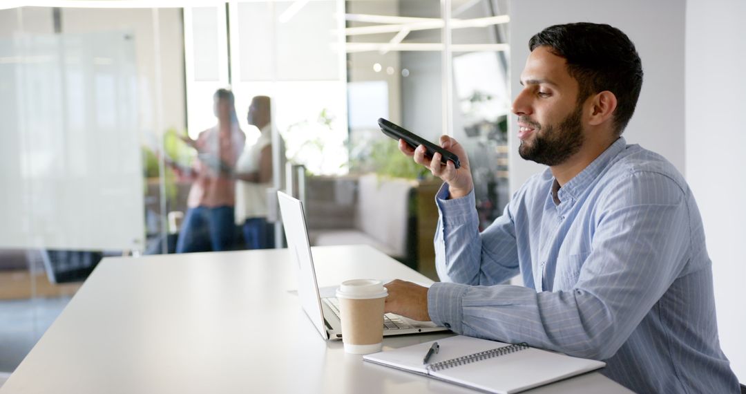 Man Using Voice Assistant on Smartphone in Modern Office Environment