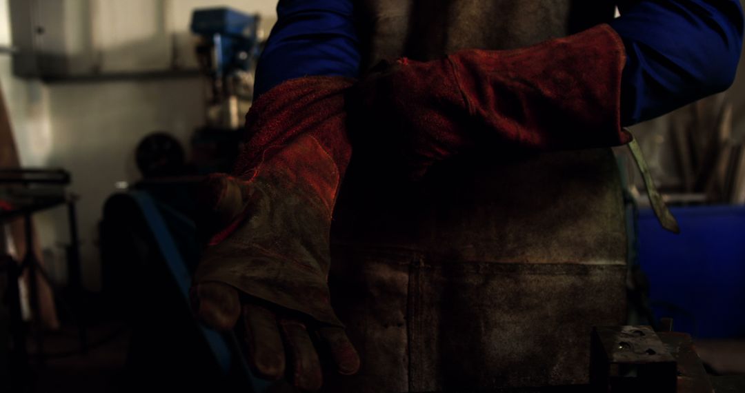 Worker Putting on Protective Gloves in Workshop - Free Images, Stock Photos and Pictures on Pikwizard.com