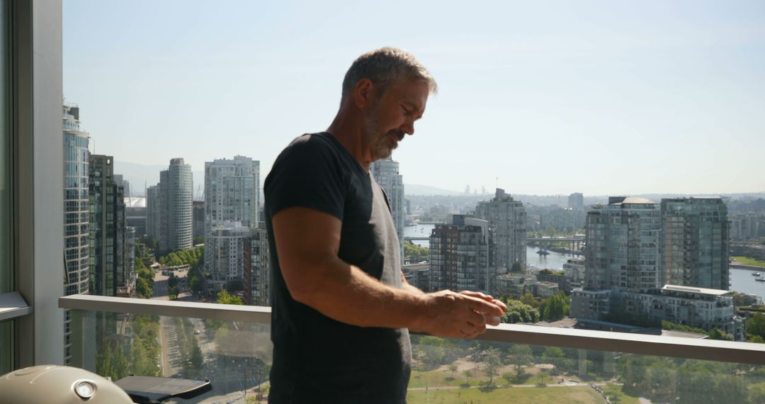 Man enjoying city view on sunny balcony with urban skyline - Free Images, Stock Photos and Pictures on Pikwizard.com