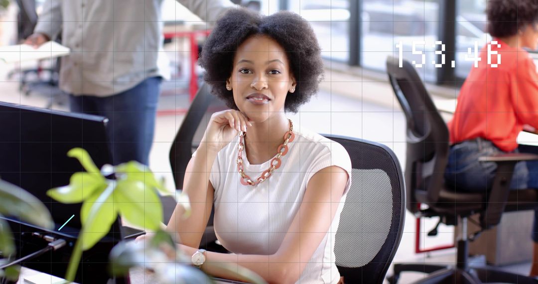 Confident Black businesswoman smiling at desk in modern open-plan office portrait, daylight