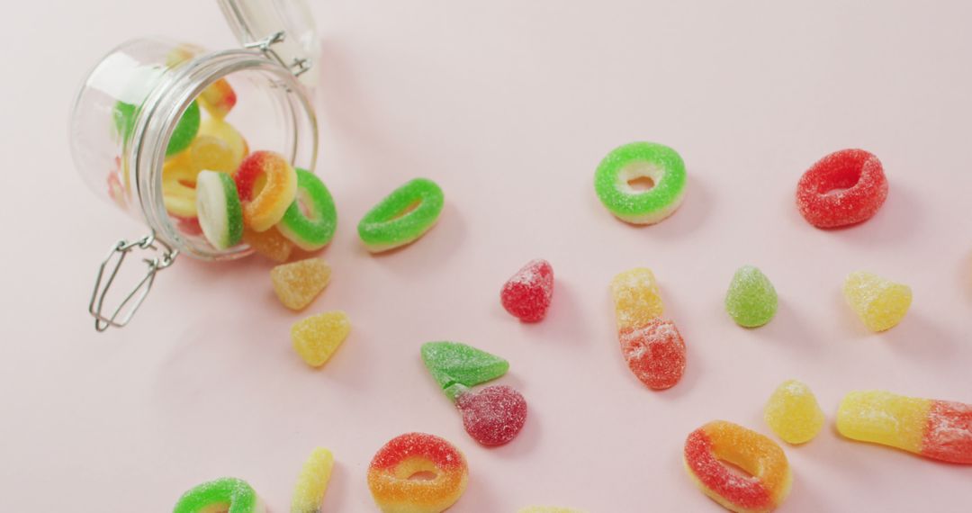 Colorful Gummy Candies Spilling from Glass Jar on Pastel Background - Free Images, Stock Photos and Pictures on Pikwizard.com