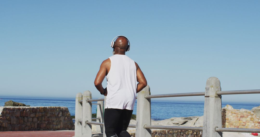 Man Jogging on Seaside Path Under Clear Blue Sky - Free Images, Stock Photos and Pictures on Pikwizard.com