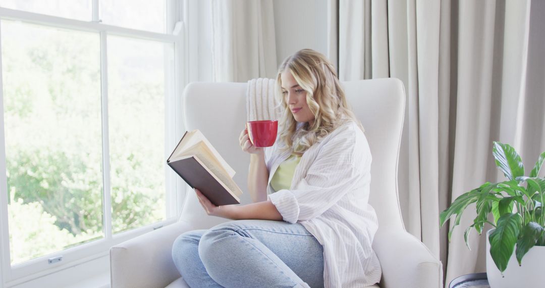 Relaxed Woman Reading Book by Bright Window with Coffee Mug - Free Images, Stock Photos and Pictures on Pikwizard.com