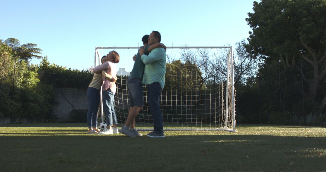 Family Embracing on Backyard Turf with Soccer Goal: Bonding and Recreation