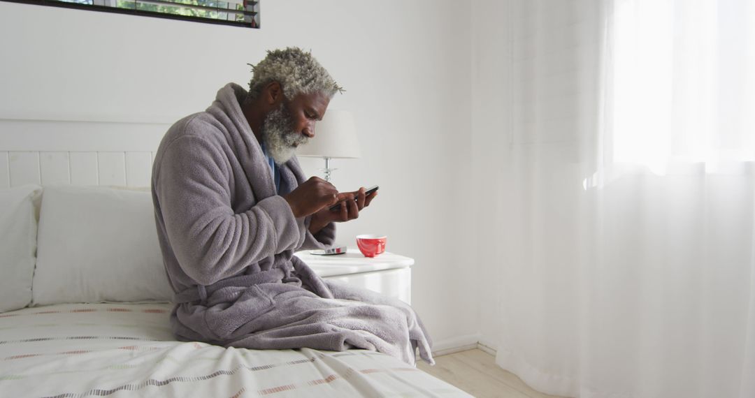 Senior African American Man in Bathrobe Using Smartphone on Bed - Free Images, Stock Photos and Pictures on Pikwizard.com