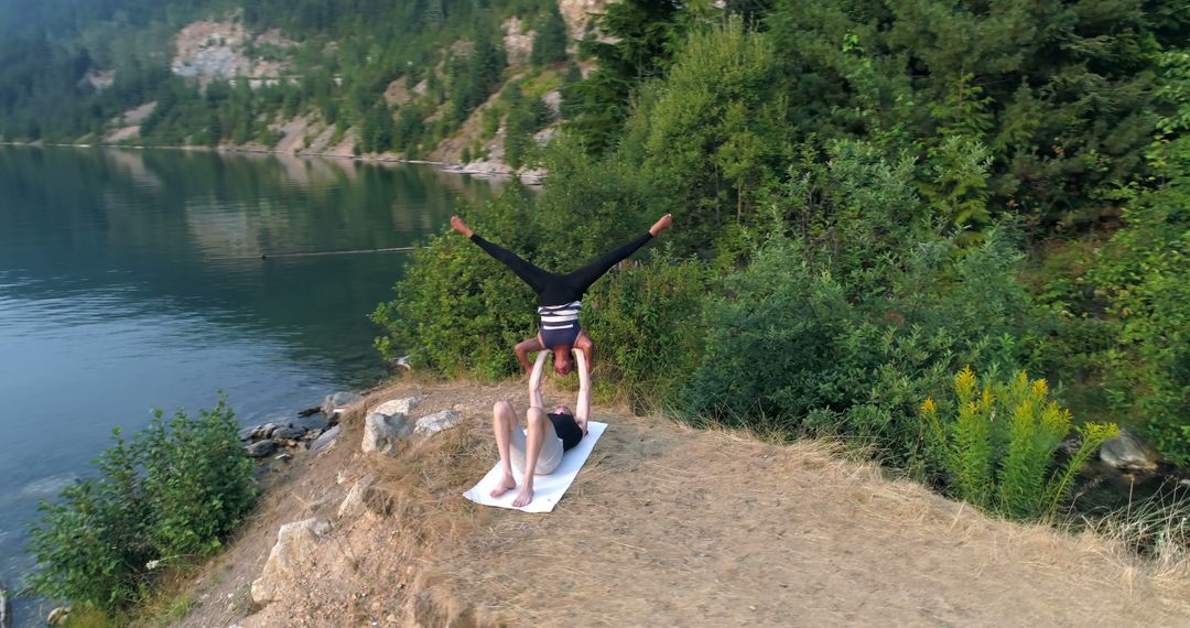 Couple Practicing Acro Yoga on Cliff Overlooking Lake - Free Images, Stock Photos and Pictures on Pikwizard.com