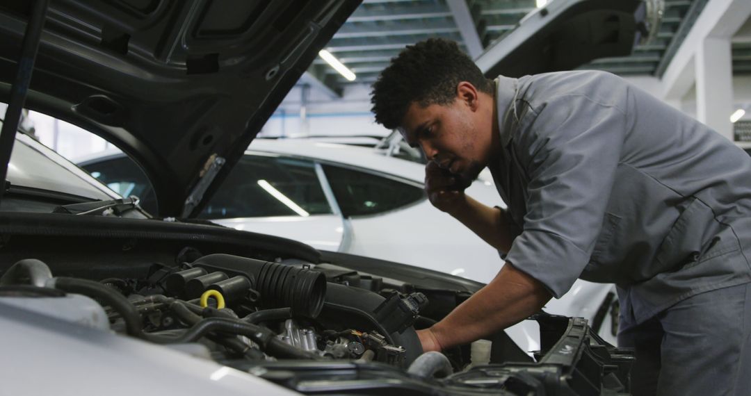 Auto Mechanic Repairing Car Engine While on Phone in Workshop - Free Images, Stock Photos and Pictures on Pikwizard.com