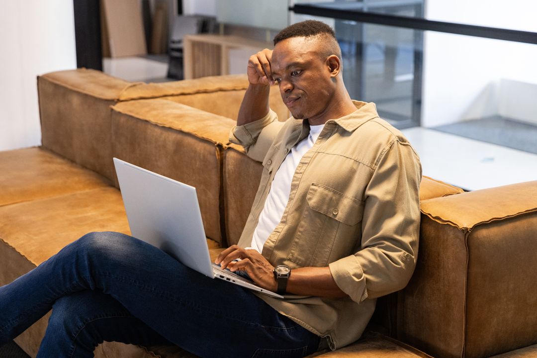 Mid Adult Man Relaxing on Couch with Laptop Work Environment