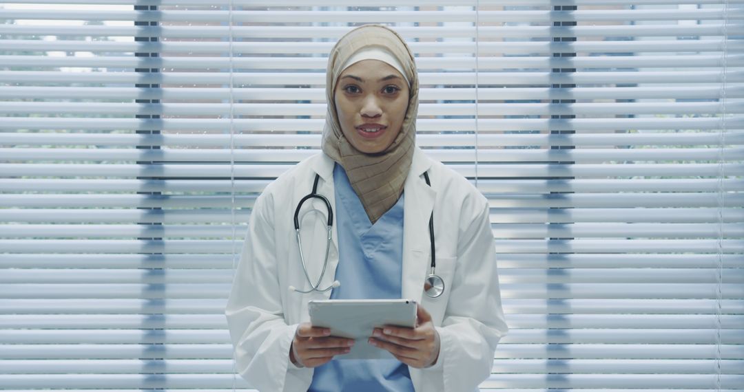 Female Doctor in Hijab Holding Digital Tablet in Medical Office - Free Images, Stock Photos and Pictures on Pikwizard.com