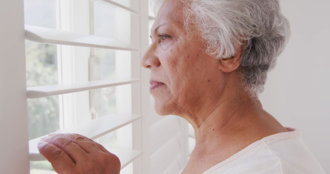 Senior Woman Looking Out Window With Shutters - Free Images, Stock Photos and Pictures on Pikwizard.com