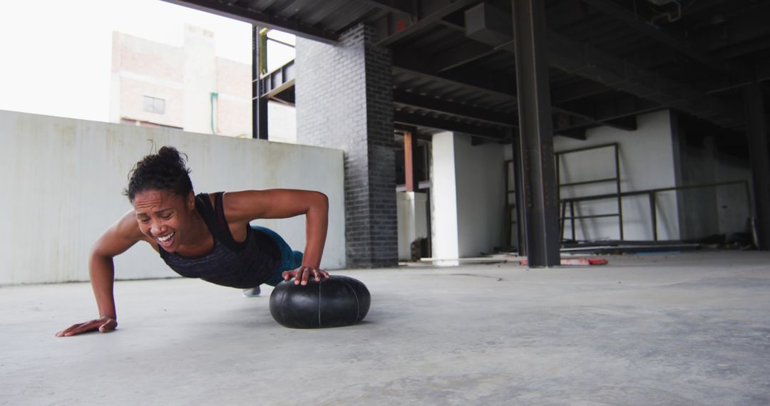 Athletic Woman Performing Push-Ups on Fitness Ball in Industrial Space - Free Images, Stock Photos and Pictures on Pikwizard.com