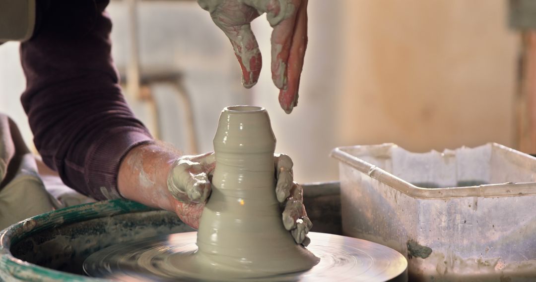 Hands Sculpting Clay Pot on Spinning Wheel in Artisan Workshop