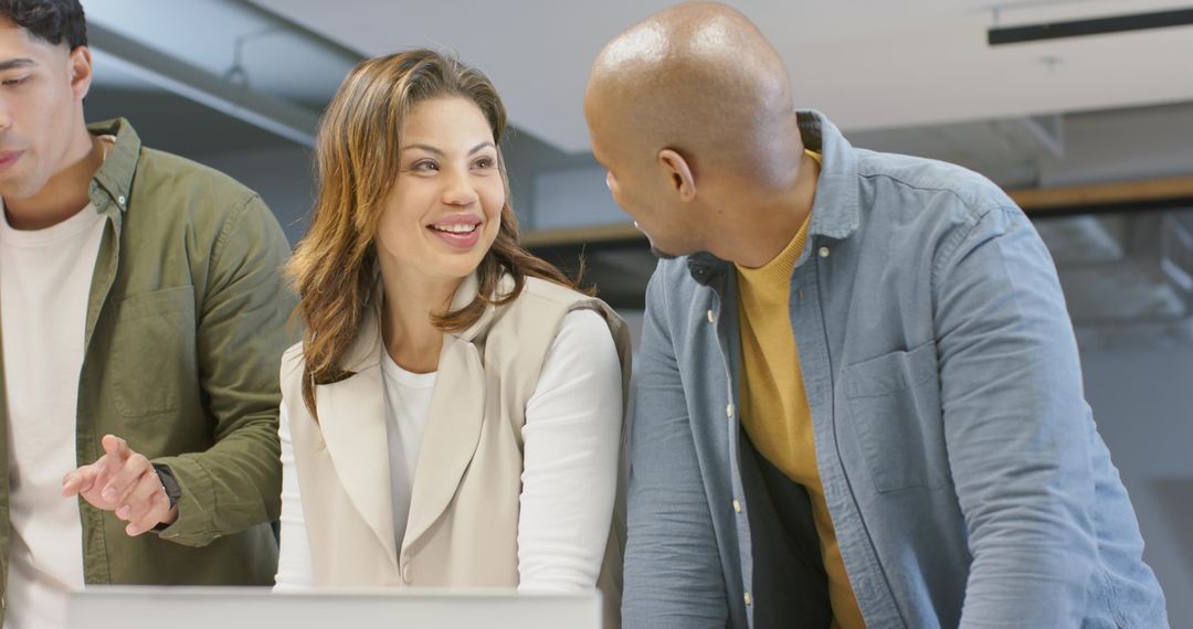 Multicultural team collaborating around laptop in modern open-plan office