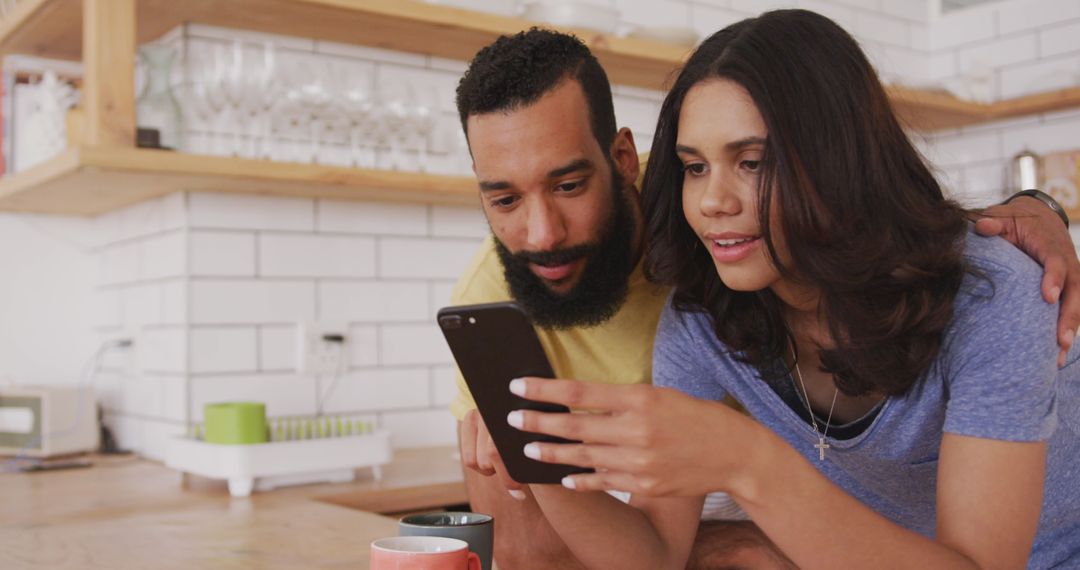 Couple Relaxing at Home with Smartphone in Kitchen
