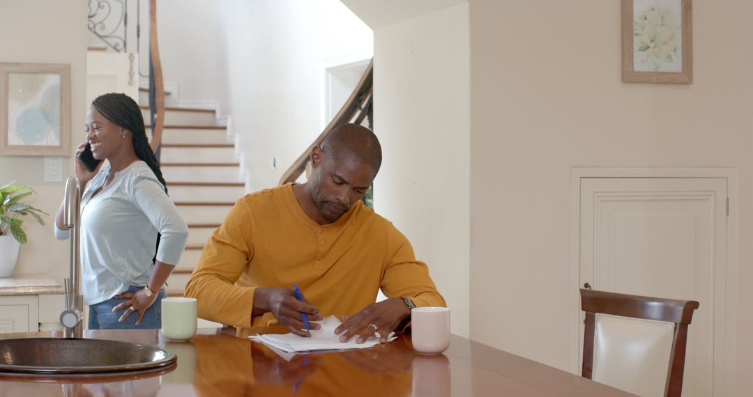 Man Analyzing Documents Home while Multitasking Woman on Phone