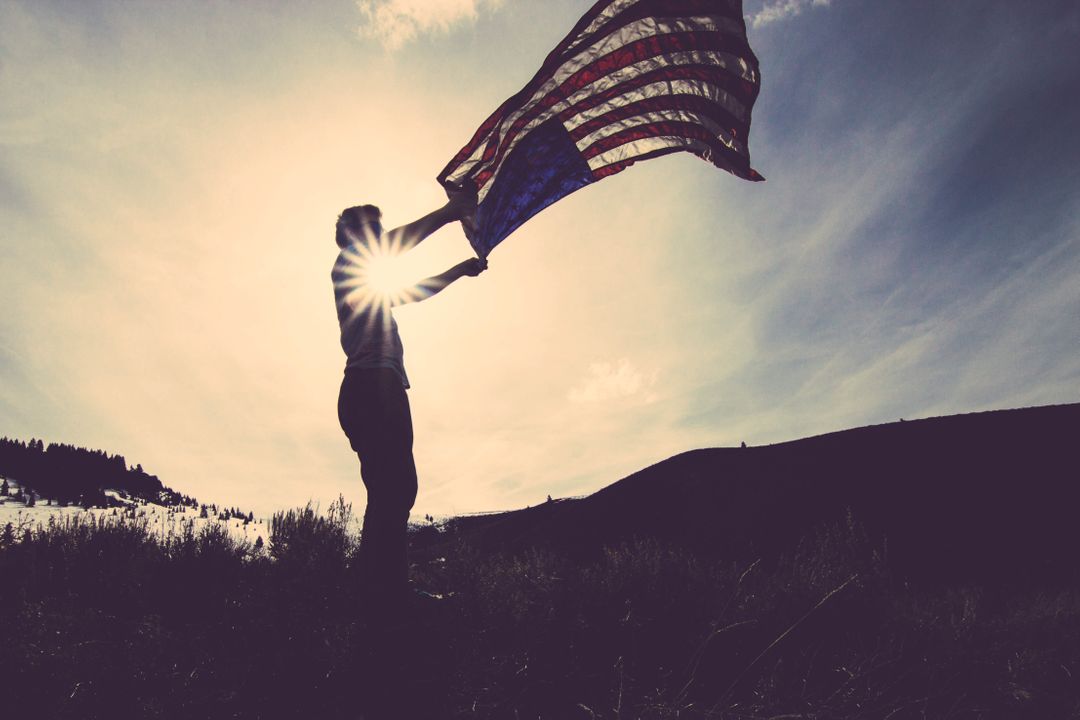 Silhouette of Person Holding American Flag Against Sunlit Background - Free Images, Stock Photos and Pictures on Pikwizard.com