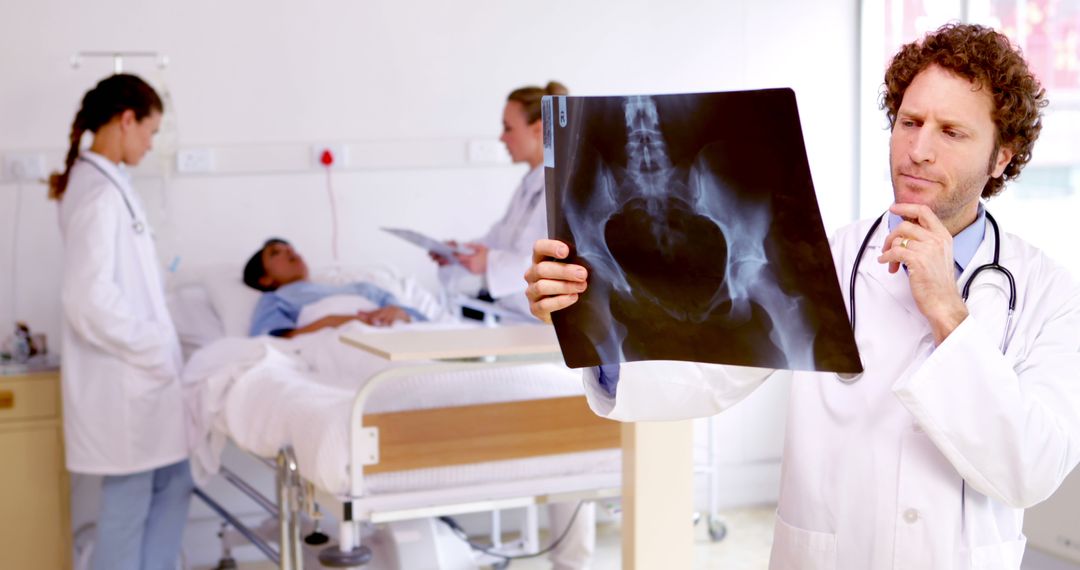 Doctor Examining X-Ray in Hospital Room with Medical Staff - Free Images, Stock Photos and Pictures on Pikwizard.com