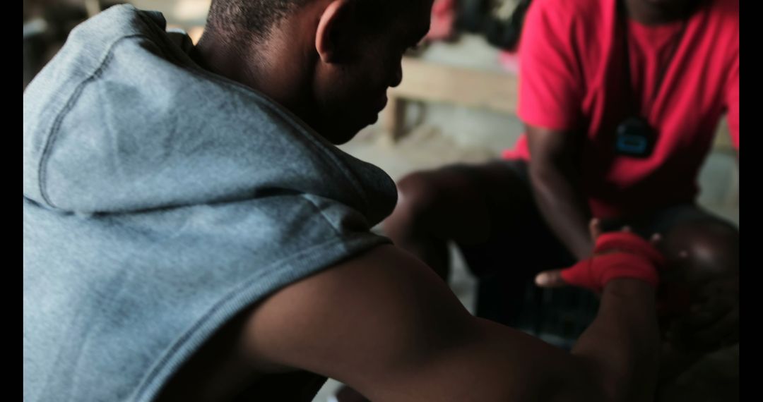 Trainer Assisting Boxer with Hand Wraps in Gym Setting