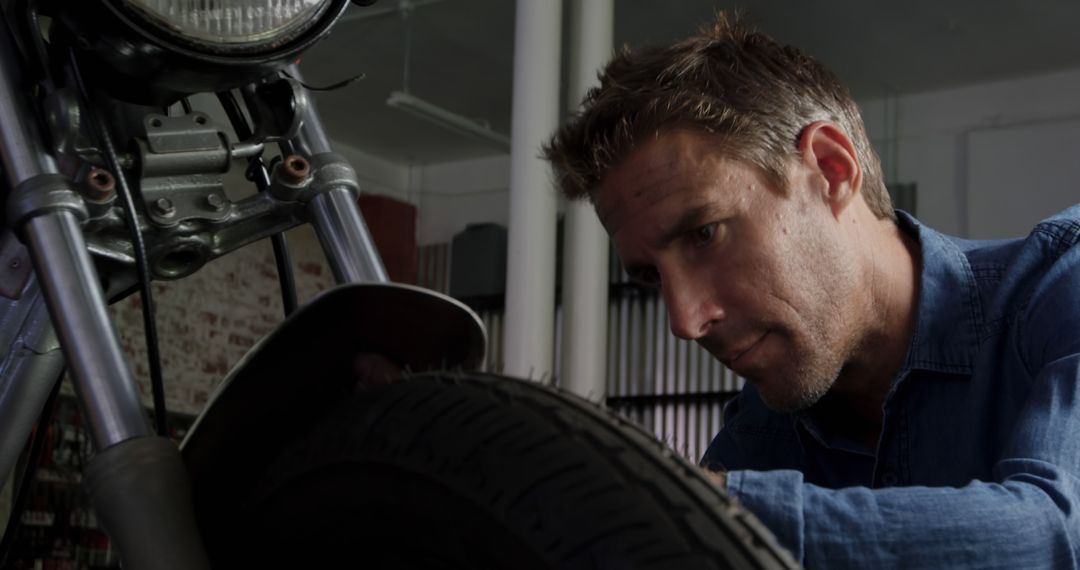 Focused Mechanic Repairing Motorcycle Tire in Workshop - Free Images, Stock Photos and Pictures on Pikwizard.com