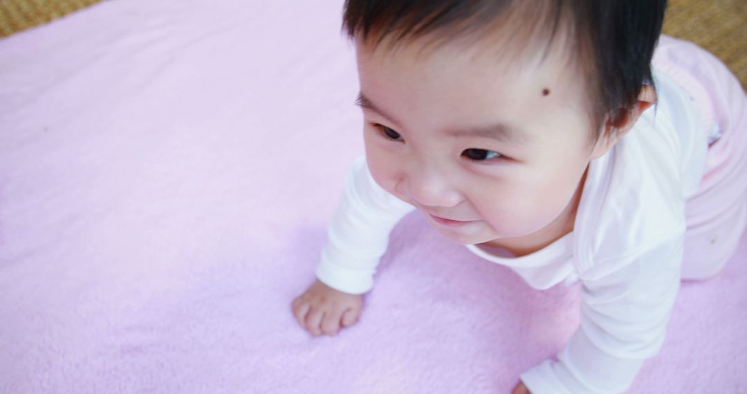 Curious Asian Baby Crawling on Soft Pink Surface