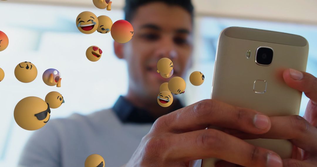 Diverse Man Engaging with Floating Emojis via Smartphone