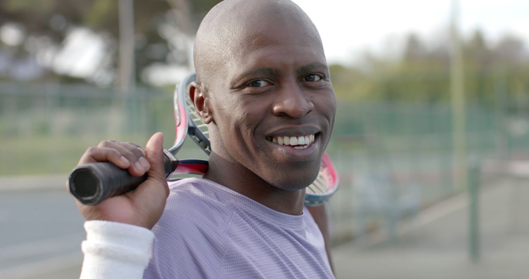 Smiling African American Man Holding Tennis Racket on Shoulder Outdoors - Free Images, Stock Photos and Pictures on Pikwizard.com