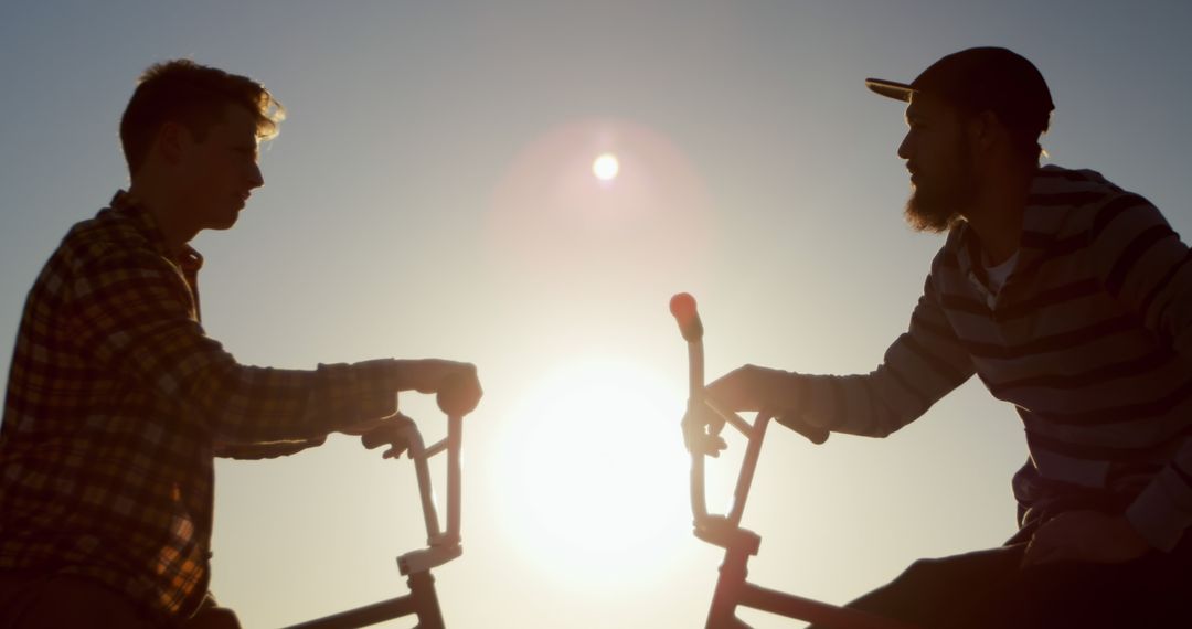 Silhouette of Two Male Friends Chatting on Their Bicycles at Sunset - Free Images, Stock Photos and Pictures on Pikwizard.com