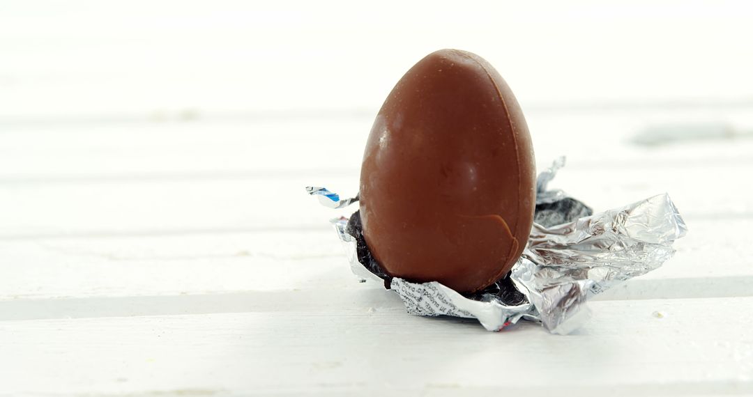 Chocolate Egg Partially Unwrapped with Aluminum Foil on White Surface - Free Images, Stock Photos and Pictures on Pikwizard.com