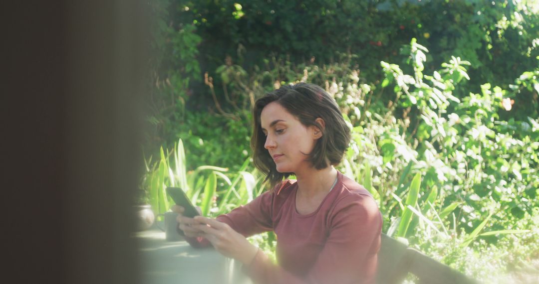 Young Woman Texting on Smartphone in Lush Garden - Free Images, Stock Photos and Pictures on Pikwizard.com