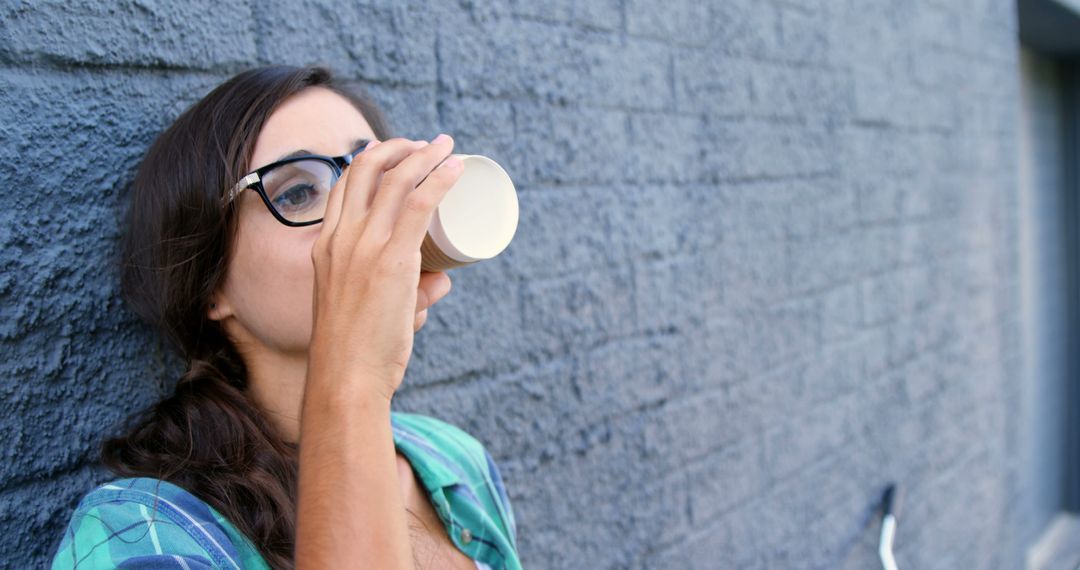 Woman drinking coffee against brick wall outdoors - Free Images, Stock Photos and Pictures on Pikwizard.com