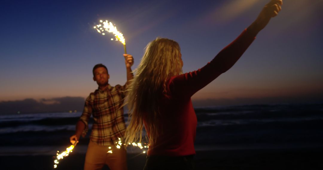 Joyful Couple Dancing with Sparklers on Evening Beach