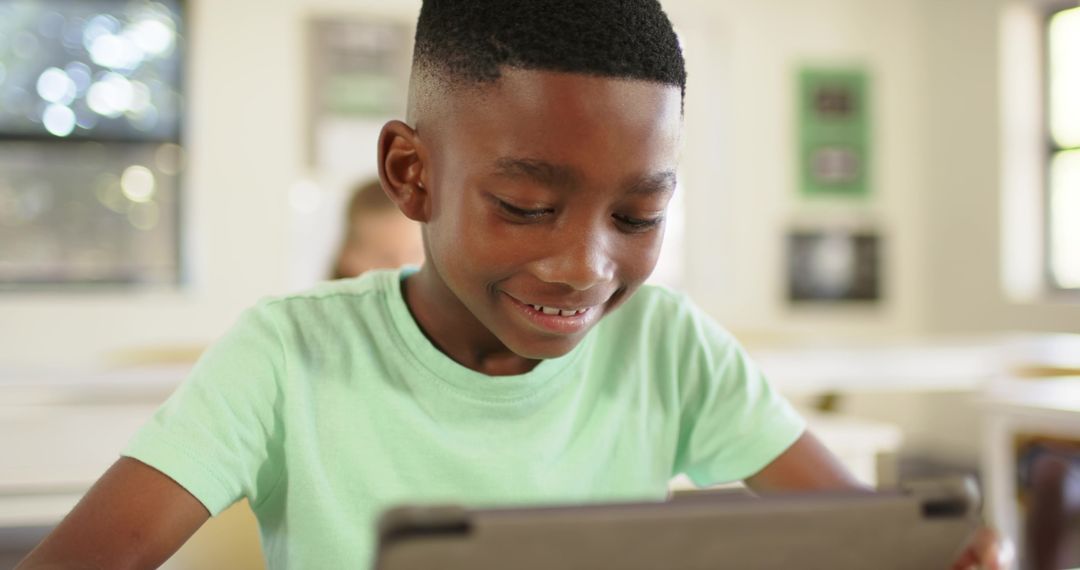 African American Boy Smiling Using Tablet in Bright Classroom Learning with Digital Device