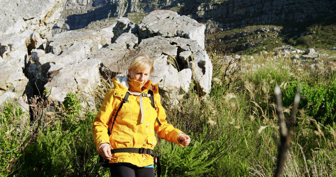 Hiker Exploring Rocky Terrain in Yellow Jacket - Free Images, Stock Photos and Pictures on Pikwizard.com