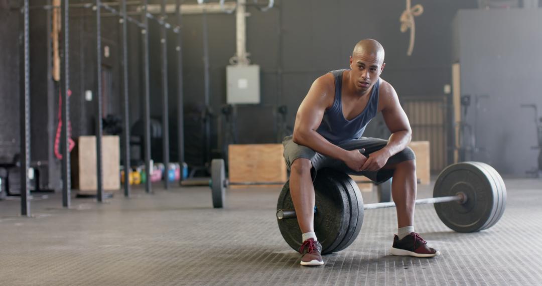 Exhausted biracial sportsman resting on weight bar and sweating at gym - Free Images, Stock Photos and Pictures on Pikwizard.com