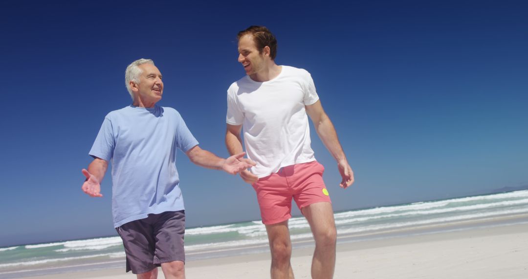 Happy Senior and Young Man Walking on Beach - Free Images, Stock Photos and Pictures on Pikwizard.com