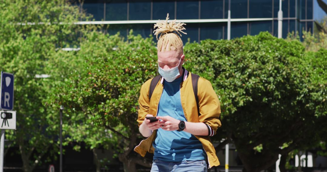 Young man wearing mask using smartphone on urban street - Free Images, Stock Photos and Pictures on Pikwizard.com