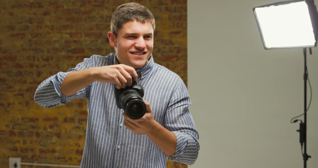 Professional Photographer Smiling While Holding Camera in Front of Studio Light - Free Images, Stock Photos and Pictures on Pikwizard.com