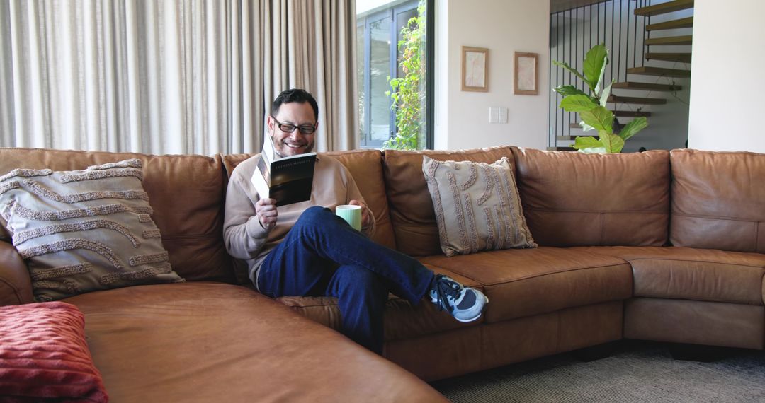 Asian Man Enjoying Quiet Reading Time on Leather Sofa in Modern Home